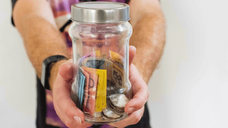 A person holding a jar of money